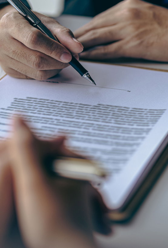 Businessman,And,Team,Discuss,With,Lawyer,About,Contract,Documents,To Close-up of man signing a legal document